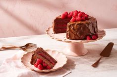 two pieces of chocolate cake with raspberries on the top and one slice missing