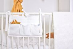 a white crib with a baby's bed in it and a blanket hanging on the wall