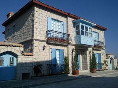 an old stone house with blue shutters on the windows and balconies in front