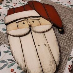 a wooden santa clause with glasses and a red hat on top of a table cloth