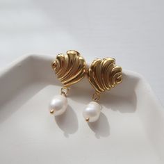 Adorned with a seashell and pearl dangle, these earrings are perfect for adding a beachy and fun flair to any look. -stainless steel, gold plated Elegant Shell-shaped Earrings, Elegant Shell-shaped Metal Earrings, Shell-shaped Pearl Charm Earrings As Gift, Gold Pearl Shell-shaped Earrings, Gold Pearl Drop Earrings In Shell Shape, Gold Shell With Pearl Drop, Elegant Pearl Charm Earrings With Shell, Gold Shell Pearl Charm Earrings, Gold Dangle Shell Earrings With Pearl Drop