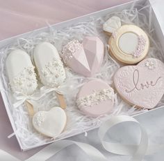 decorated cookies in a box with ribbons and ribbon on the table next to it,