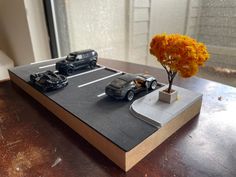 toy cars are parked on top of a table next to a vase with an orange flower