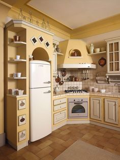 a kitchen with yellow walls and white appliances on the counter top, along with brown tile flooring