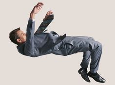 a man in a suit and tie is flying through the air with his feet up