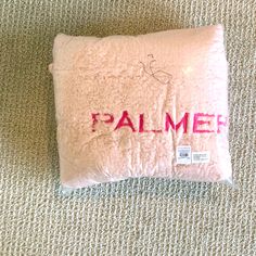 a pink pillow with the word palmer on it sitting on top of a carpeted floor