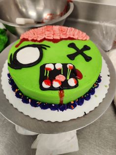 a green cake decorated to look like a zombie with eyeballs and blood on it