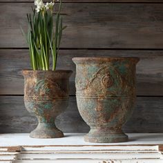 two vases with flowers in them sitting on a table