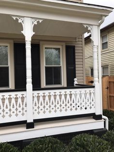 a white porch with black shutters in front of a house