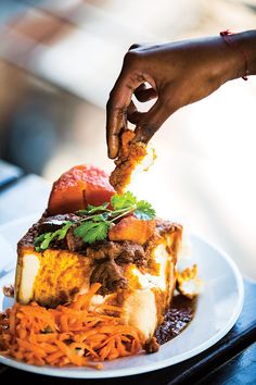 a person is dipping some food on top of a piece of meat and carrots