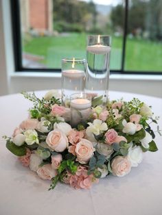 a centerpiece with candles and flowers on a table