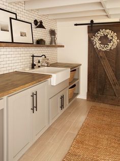 a kitchen with a sink, cabinets and an open barn door in the wall behind it