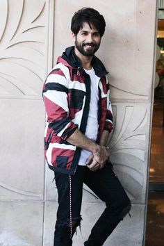 a man standing in front of a wall with his hand on his hip and smiling