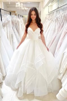 a woman standing in front of white dresses