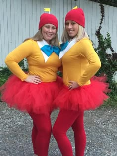 two women dressed in costumes standing next to each other on the gravel ground with their hands on their hipss