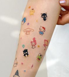 a woman's arm with many stickers on it, including cats and kittens