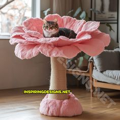 a cat sitting on top of a pink flower shaped scratching post in a living room