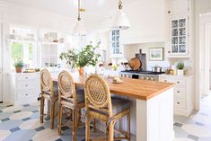 a kitchen with white cabinets and wooden counter tops next to a dining room table filled with chairs