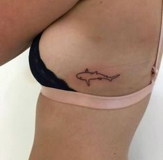 a woman's stomach with a small tattoo of a shark on the right side