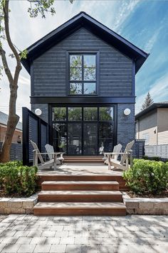 a house that has stairs leading up to the front door and patio area with chairs