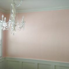 a chandelier hanging from the ceiling in a room with pink walls and white trim