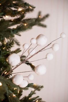 a close up of a christmas tree with white balls hanging from it's branches