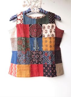 a colorful patchwork top hanging on a wall