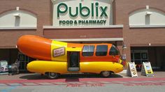 a large hot dog shaped like a car parked in front of a publix