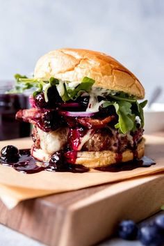 a burger with blueberries and lettuce on a cutting board