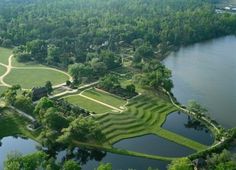 an aerial view of a large grassy area next to a lake and park with lots of trees