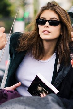 a woman wearing sunglasses and holding an umbrella