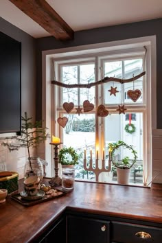 a kitchen counter with candles, potted plants and other decorations on the window sill