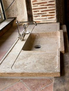 a bathroom sink sitting on top of a counter next to a window with a brick wall behind it