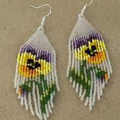 a pair of earrings made out of seed beads with colorful flowers on the front and back