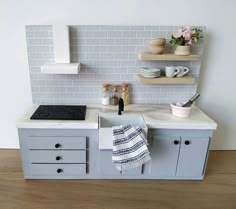 a toy kitchen with grey cabinets and white counter tops, including a stove top oven