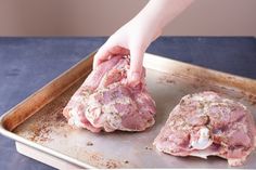 two raw meats on a baking sheet being held by a person's hand