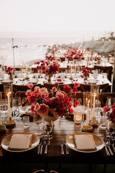 the table is set with flowers and candles for an elegant wedding reception by the ocean