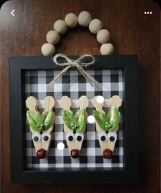 three wooden reindeer ornaments in a frame on a table with a string attached to it