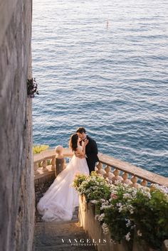 a bride and groom kissing on the steps by the water at their wedding venue in italy