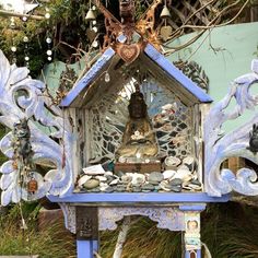 there is a small shrine in the middle of some plants and rocks with a buddha statue on top