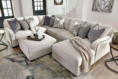 a living room filled with lots of furniture and pillows on top of a wooden floor