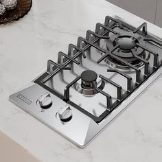 a silver stove top sitting on top of a counter next to a plate with donuts