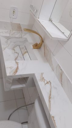 a white bathroom with marble counter tops and gold faucet