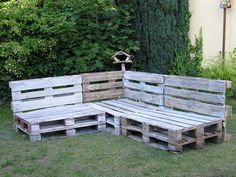 a wooden bench made out of pallets sitting in the grass