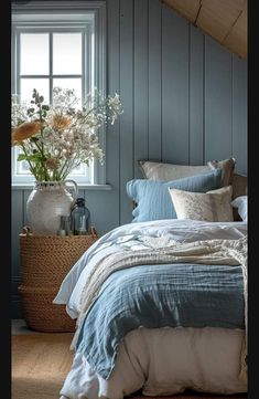 a bed sitting under a window next to a basket with flowers on top of it