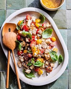 a white plate topped with salad next to a wooden spoon