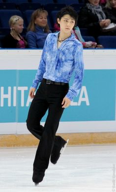 a man in blue shirt and black pants skating on ice