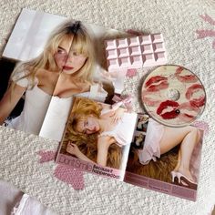 an image of a woman laying on top of a bed next to magazines and other items