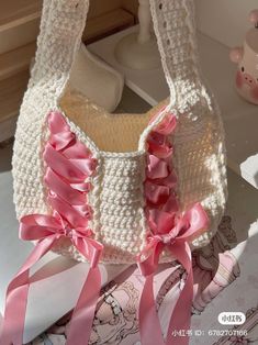 a crocheted purse with pink ribbon on it sitting on top of a table