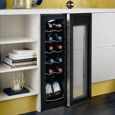 a wine cooler in the corner of a kitchen with yellow walls and black flooring